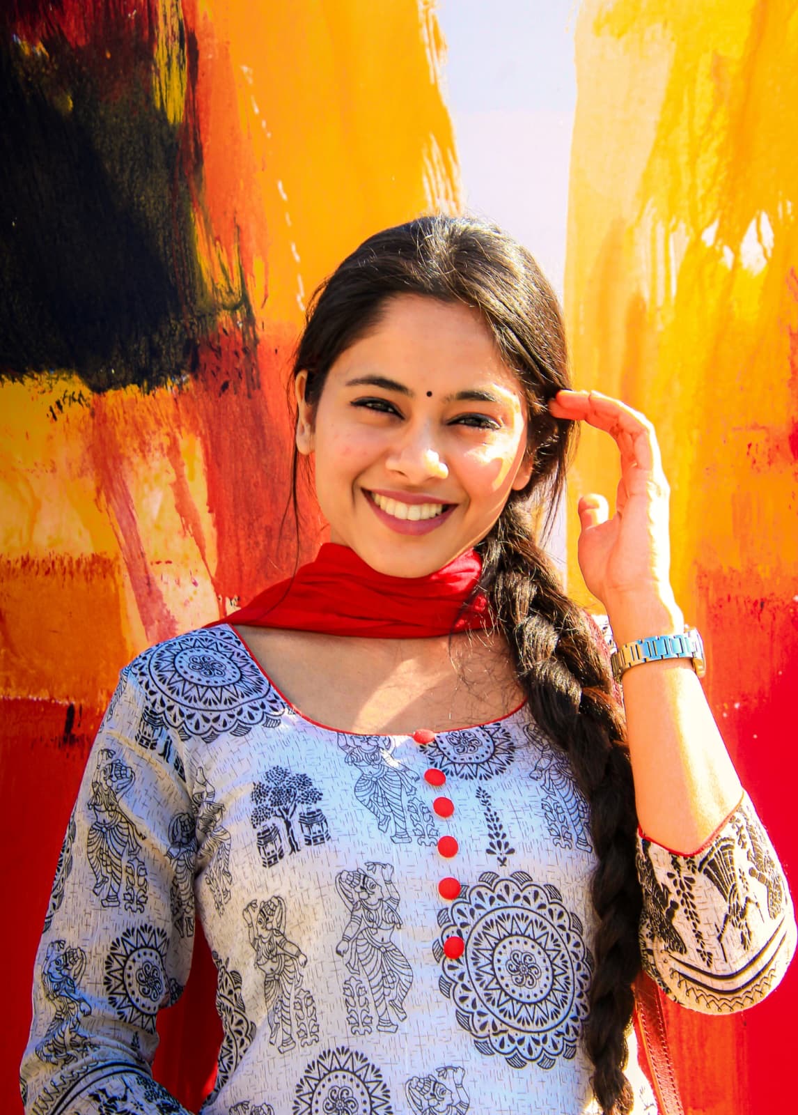 Raman Gill smiling in front of a colourful painted wall